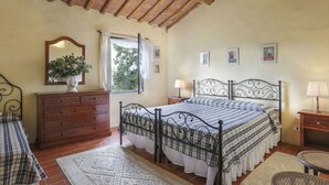 A bedroom with a bed, a dresser, a window with curtains, and a view of trees outside. - Favilli (PAA130) by Interhome (Palaia)