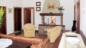 Een woonkamer met een open haard, twee fauteuils, een bank en een salontafel.