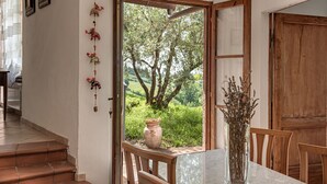 Un comedor con una mesa de mármol, sillas de madera y vista a un jardín exuberante a través de un ventanal abierto.