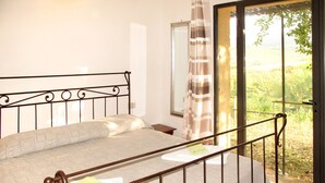 Un dormitorio con una cama, una ventana y vistas a la vegetación.