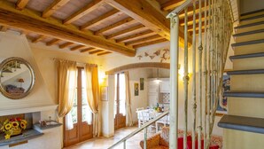 Un vaste espace de vie doté d’un plafond en bois, d’un escalier et d’un coin repas avec une table et des chaises.