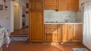 A kitchen with wooden cabinets, a tiled backsplash, and a sink. - Conte Francesco II by Interhome (Certaldo)