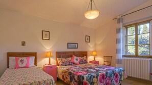 Ein gemütliches Schlafzimmer mit zwei Betten, floralen Bettdecken, Nachttischlampen und einem Fenster mit Blick.