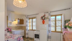 Eine Küche mit Fliesenboden, einem Kühlschrank, einer Spüle und einem Fenster mit Vorhängen.