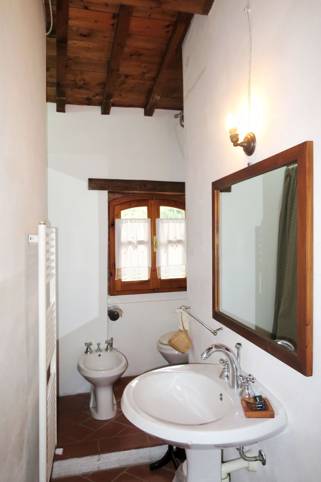 Et badeværelse med træloft, et stort spejl, en vask og et toilet.