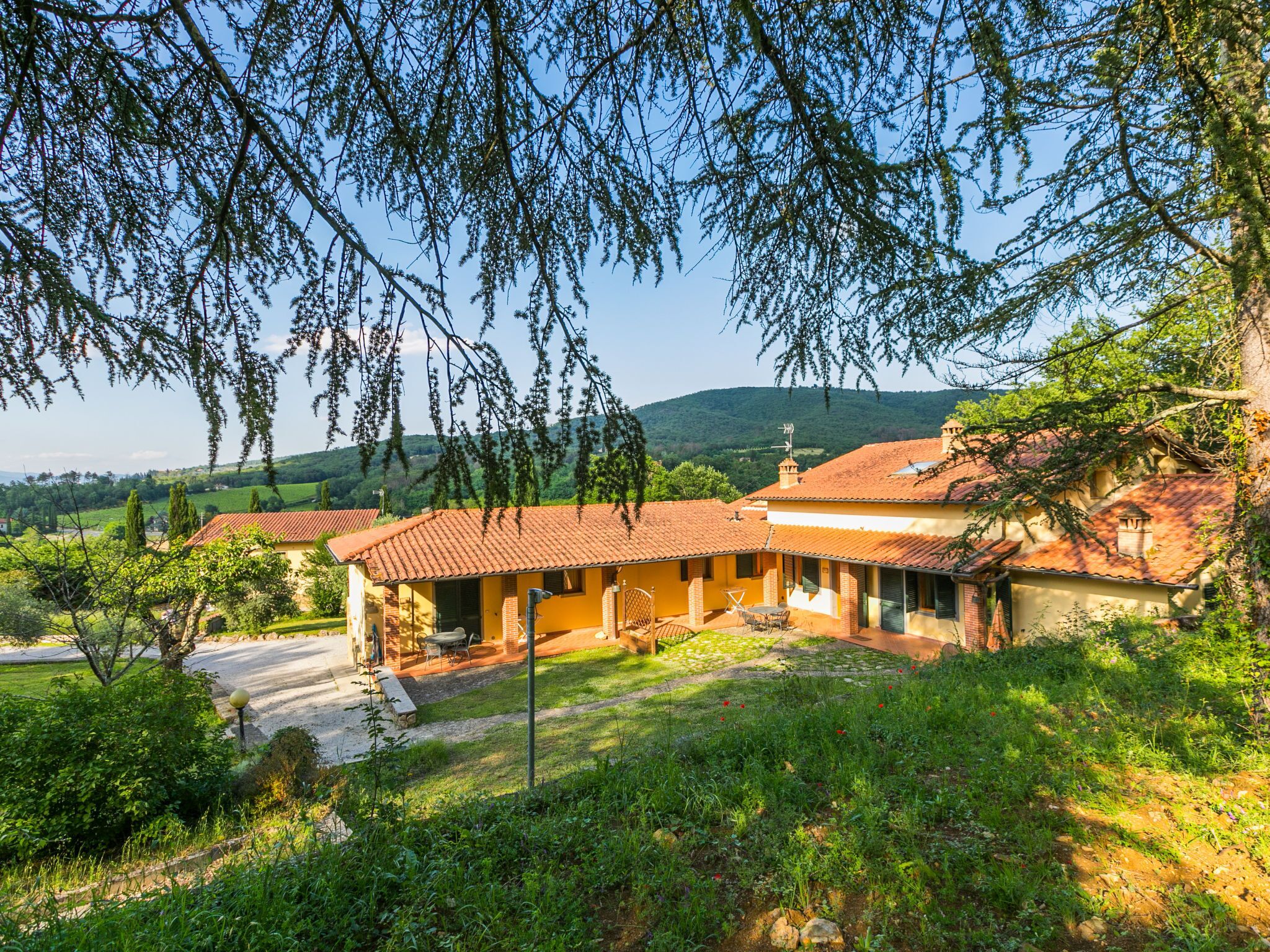 Une villa de style rustique, dotée d’un toit en tuiles, d’un patio avec mobilier d’extérieur et d’un jardin luxuriant.