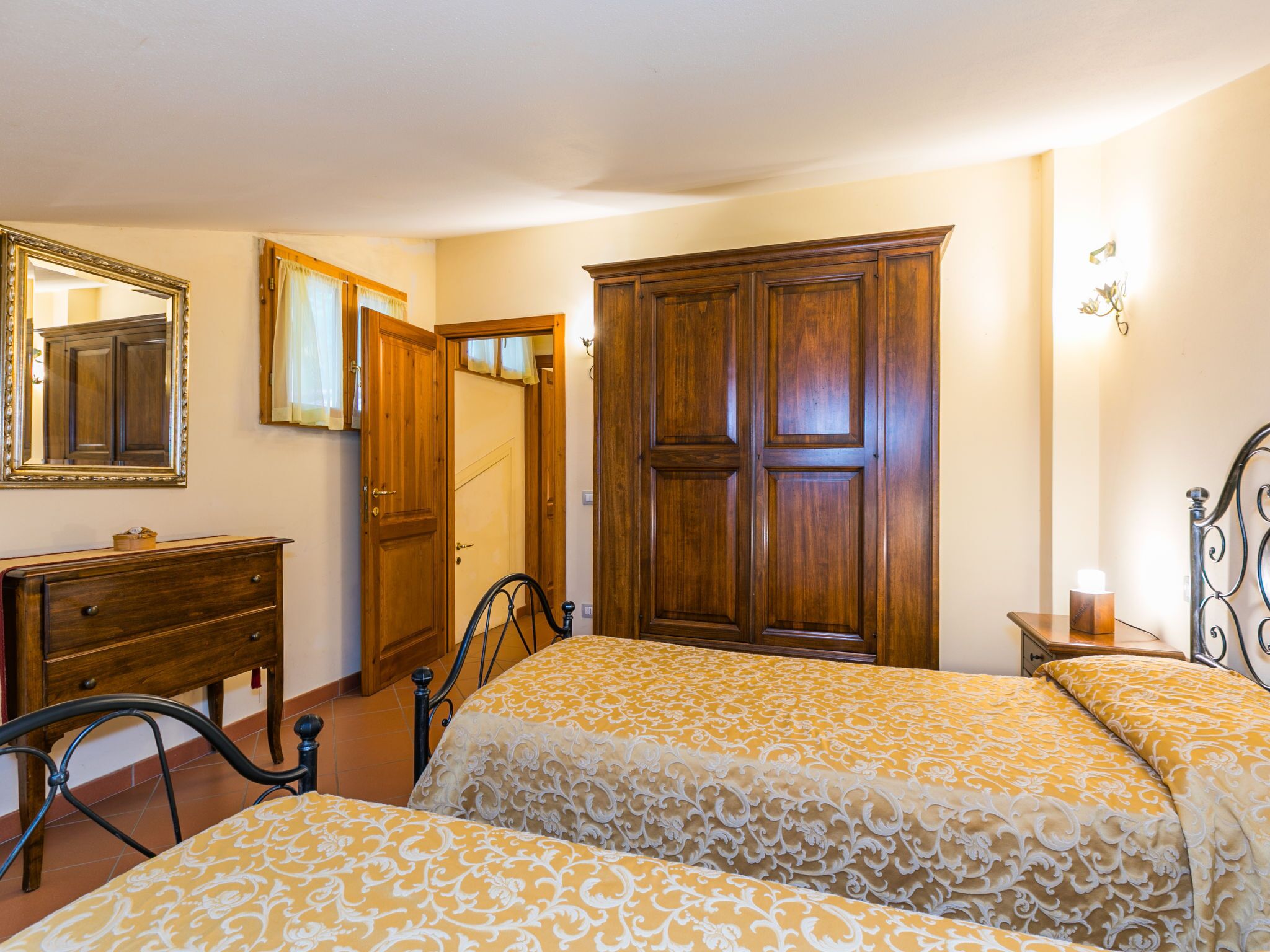 Un dormitorio con dos camas, un aparador, un armario, un espejo y una mesita de noche.