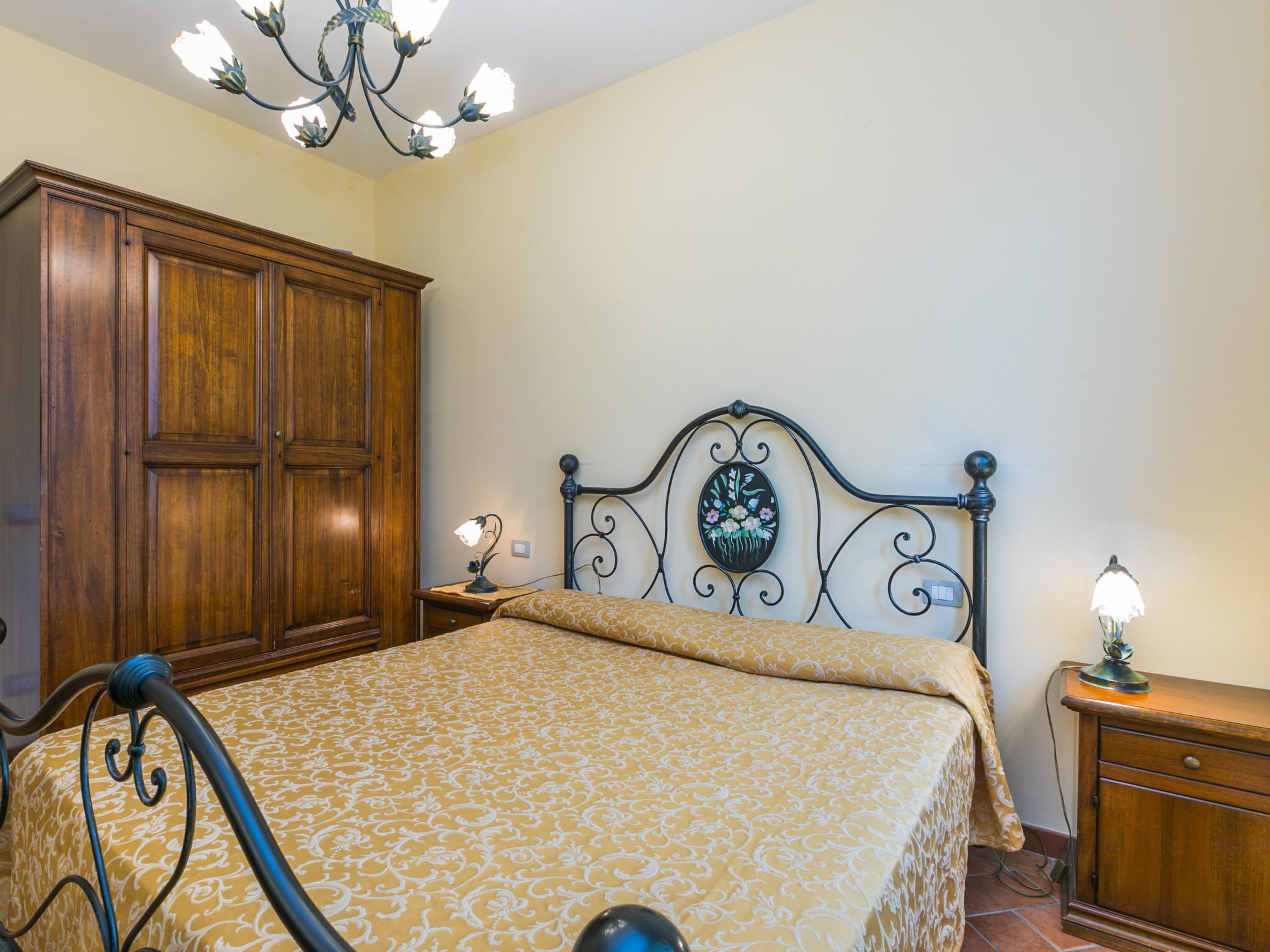 Une chambre à coucher avec un lit, une armoire en bois et un lustre.