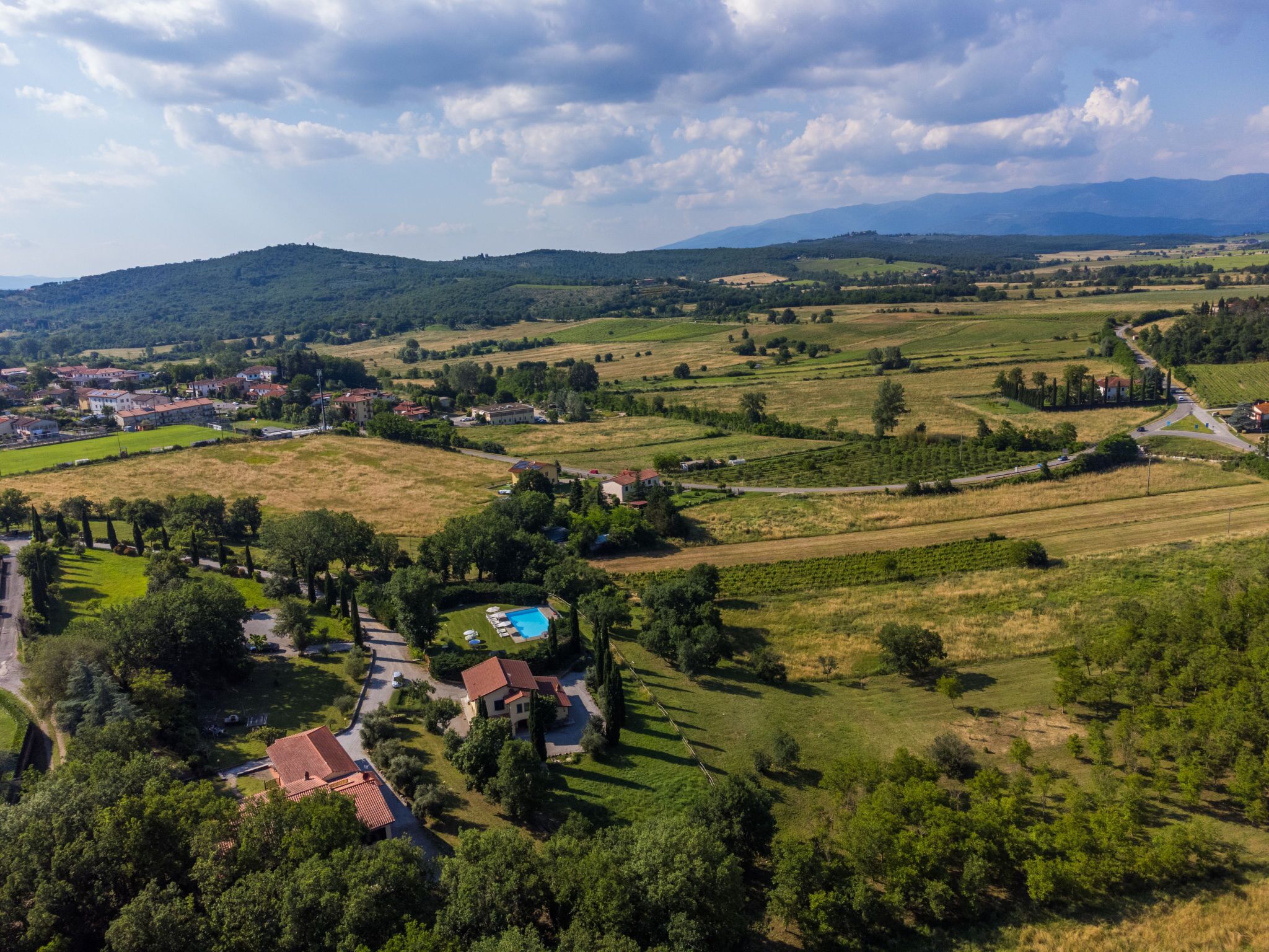 Vue aérienne d’une zone rurale avec des champs, une piscine et des maisons.
