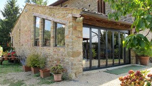 Una casa de piedra con ventanas grandes y un porche cubierto.