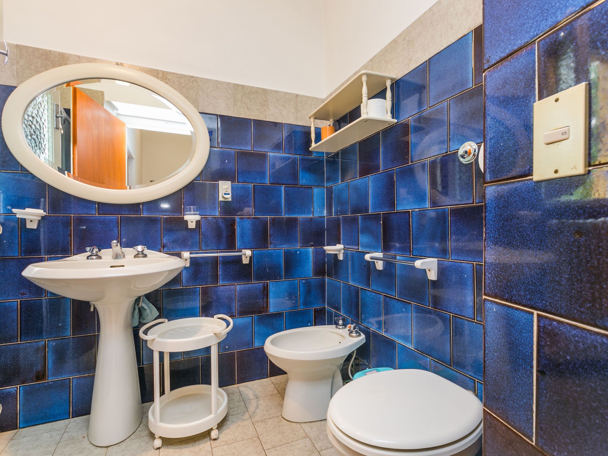 A bathroom with a white sink, a bidet, a toilet, and a mirror.