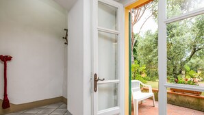 A staircase leading to a room with a white door, a red rope, and a view of a garden with a bench and chair. - San Lazzaro by Interhome (Monsummano Terme)