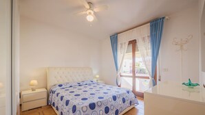 A bedroom with a bed, a nightstand, a dresser, a ceiling fan, and a window with curtains. - Dei Fiori by Interhome (Lido di Camaiore)