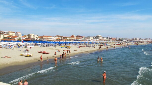 A beach with numerous umbrellas and sun loungers, a clear sky, and buildings in the background. - Dei Fiori by Interhome (Lido di Camaiore)