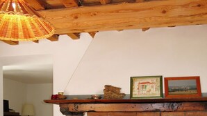 A dining area with a brick fireplace, wooden ceiling beams, and a table set with plates and glasses. - L'Uccelliera by Interhome (San Giuliano Terme)