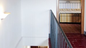 A staircase with a red-tiled floor leading to a bedroom with a wooden headboard and a metal bed frame. - L'Uccelliera by Interhome (San Giuliano Terme)