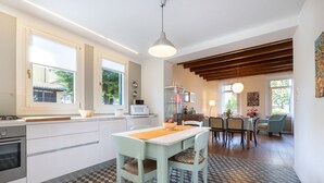Een moderne keuken met een zwart-wit geruite vloer, een eethoek met een tafel en stoelen, en uitzicht op het groen buiten.