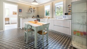 Een moderne keuken met witte kasten, een eettafel met stoelen en een vloer met een patroon.