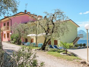 Un edificio de fachada roja, un árbol en primer plano y vista al mar.