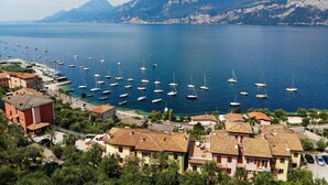 A coastal town with a marina filled with sailboats, surrounded by residential buildings with red-tiled roofs. - Casa Maria by Interhome (Brenzone)