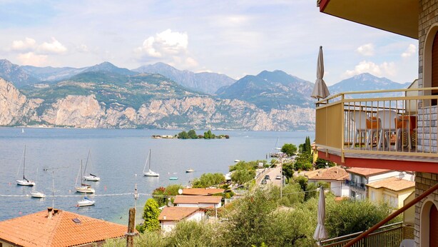 Ein Balkon mit Blick auf einen See, Boote und Berge.