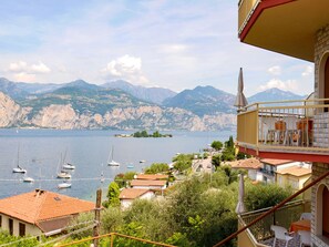 Un balcon avec vue sur un lac, des bateaux et des montagnes.