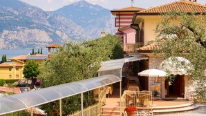 Eine Villa im mediterranen Stil mit einer Terrasse mit Blick auf einen See und Berge.