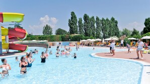 A swimming pool area with multiple water slides, surrounded by lounge chairs and umbrellas. - Apartment Eden by Interhome (Peschiera del Garda)