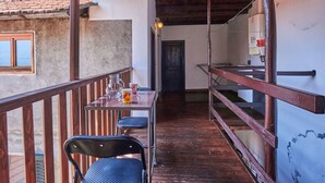 A balcony with a wooden railing, a table with chairs, and a view of a mountain.