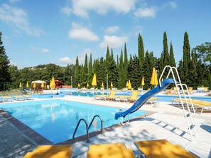 A swimming pool with a slide, sun loungers, and yellow umbrellas. - Mobilhome E (AEG403) by Interhome (Albenga)