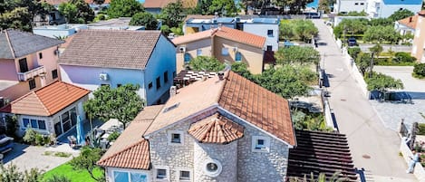 A coastal town with stone buildings, a clear blue sea, and a paved street.