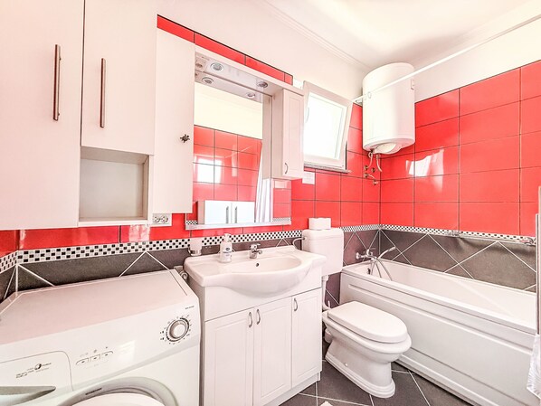 A compact bathroom with a washing machine, a sink, a toilet, and a bathtub. - Mirjana by Interhome (Nin)