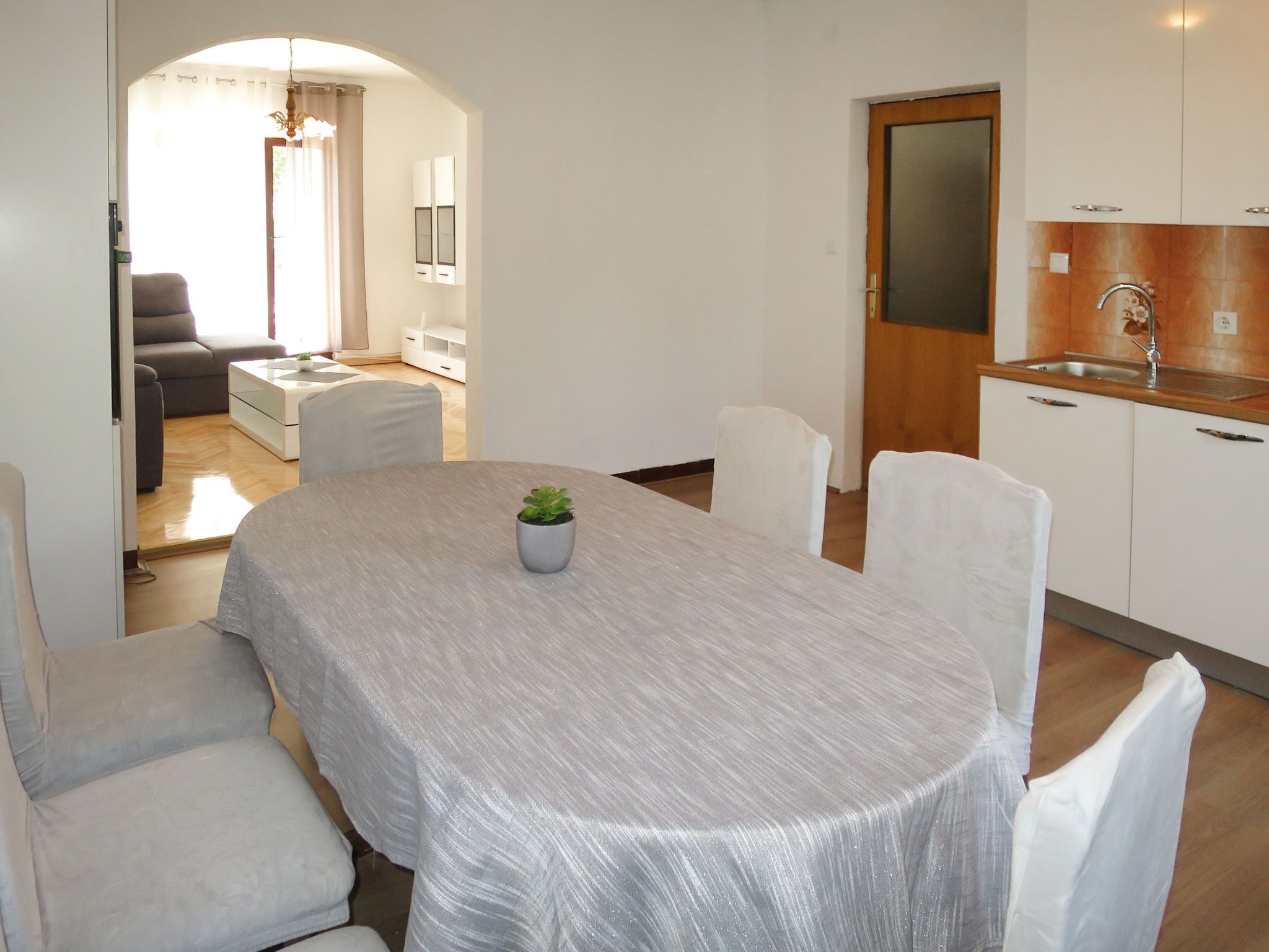 A modern, well-lit living room with a sofa, a coffee table, and a dining table set for four.