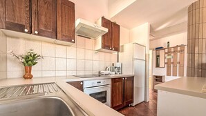 Een moderne keuken met houten kastjes, een inbouwoven, een koffiezetapparaat en een roestvrijstalen spoelbak.