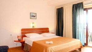 Ein Hotelzimmer mit einem hölzernen Bett, einem Nachttisch mit Lampe, einem Bild an der Wand und einem Fenster mit Vorhängen.
