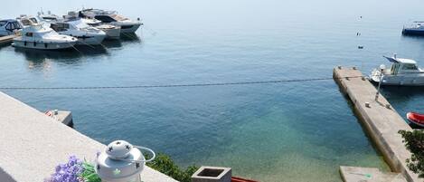 A marina with boats docked, a clear view of the water, and a lantern on a balcony.