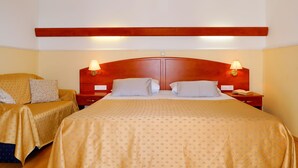 A hotel room with a large bed, two bedside tables with lamps, a wooden headboard, and a chair with a patterned cover. - Apartment Ana by Interhome (Rab/Rab)