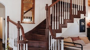 A wooden staircase with white balusters, a mirror above it, and a bed with a white comforter in the room below. - Tranquil Pet-Friendly Bungalow in Midtown Springfield with High-Speed Wi-Fi (Springfield)