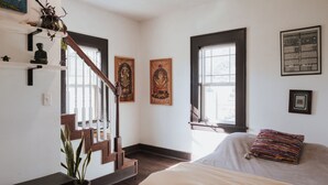 A bedroom with a bed, a staircase, a potted plant, and artwork on the walls. - Tranquil Pet-Friendly Bungalow in Midtown Springfield with High-Speed Wi-Fi (Springfield)