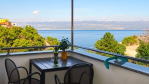 Een balkon met een tafel, stoelen en een bloempot.