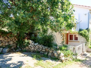 Set amidst lush greenery, this serene residence features a charming stone wall and a balcony.