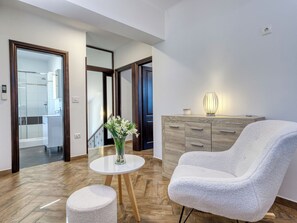 A modern living room with a white armchair, a round wooden table, and a vase of flowers. - Villa Toni by Interhome (Opatija)