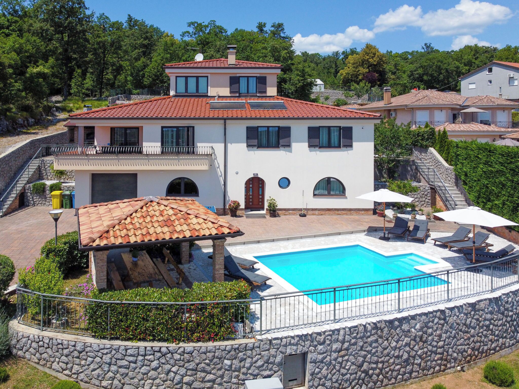 A two-story house with a swimming pool, stone walls, and a balcony.