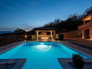 A swimming pool with two lounge chairs and a pergola, surrounded by stone walls and trees. - Villa Toni by Interhome (Opatija)
