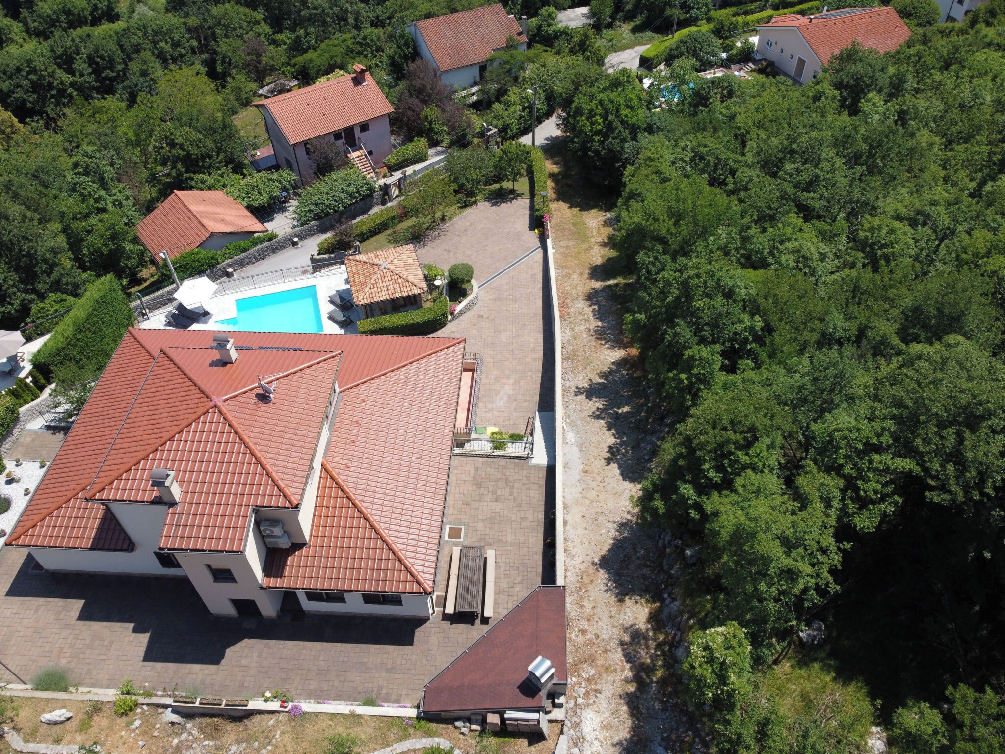 An aerial view of a residential area with houses, a swimming pool, and a large building with a red roof.