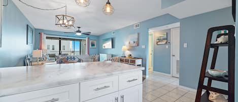 A kitchen with white cabinets, a marble countertop, and pendant lighting.