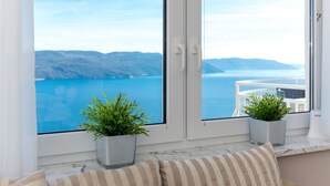A room with a large window overlooking a coastal view, a marble floor, and two potted plants on the windowsill. - Filip & Katja by Interhome (Mošćenička Draga)