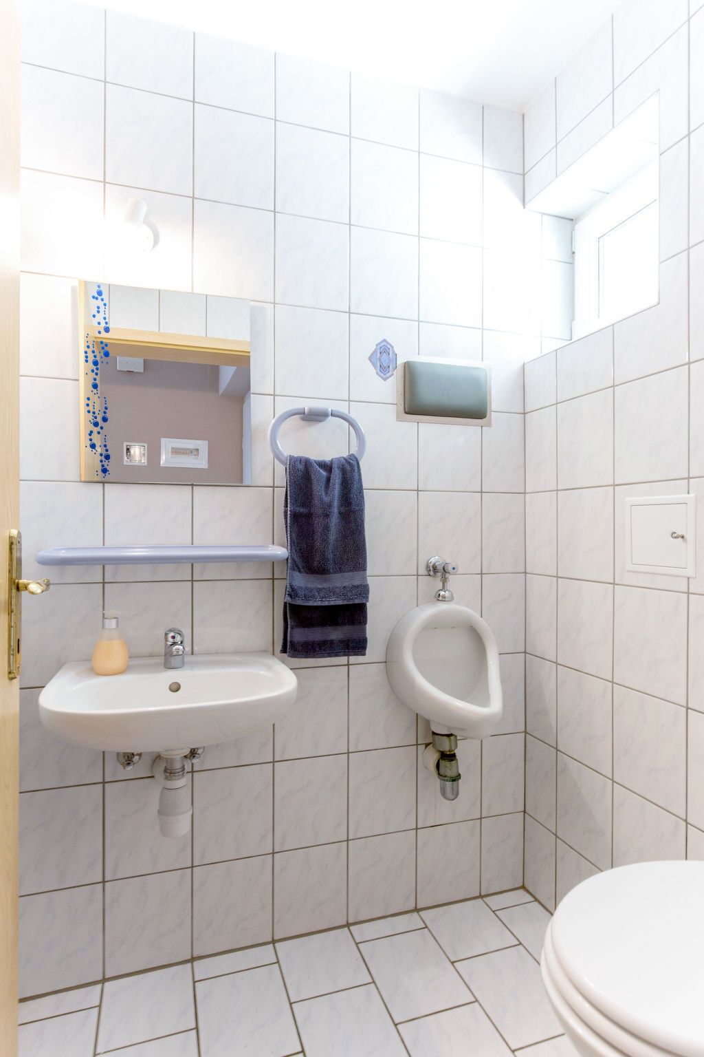 A bathroom with a sink, mirror, urinal, and toilet.