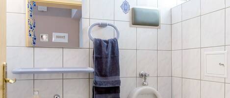 A bathroom with a sink, mirror, urinal, and toilet.