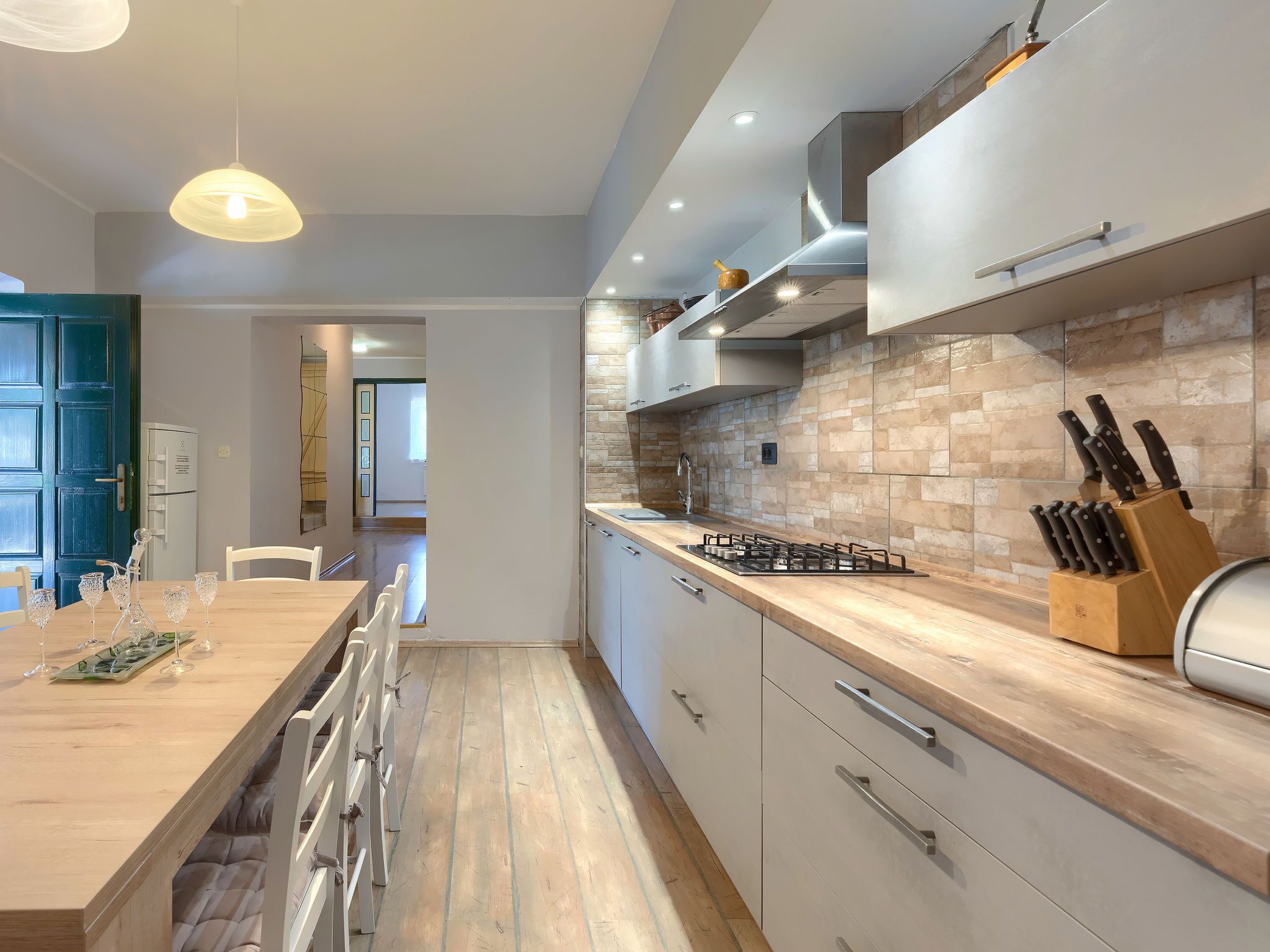 A modern kitchen with a wooden countertop, stainless steel appliances, and a knife block.